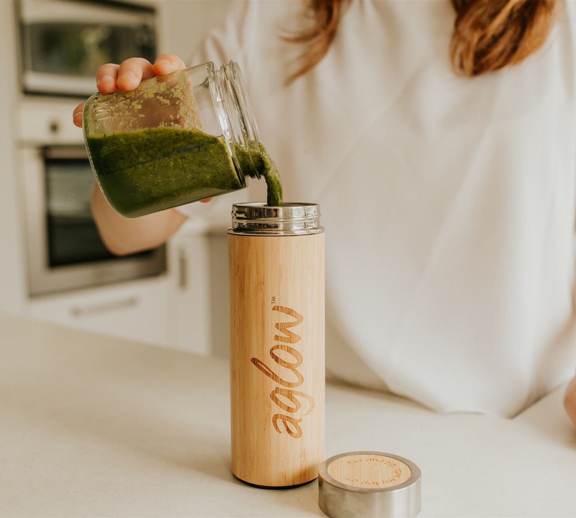 Premium bamboo drink shaker with a greens smoothie being poured in